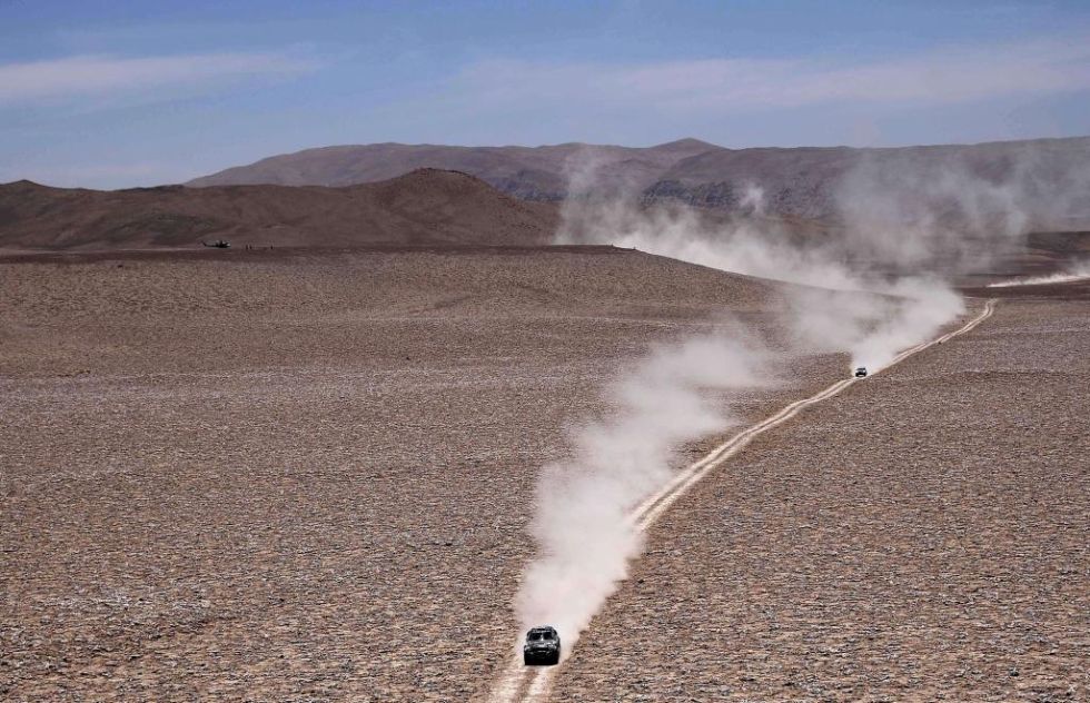 Varios coches siguen el resto del primero por el desierto.