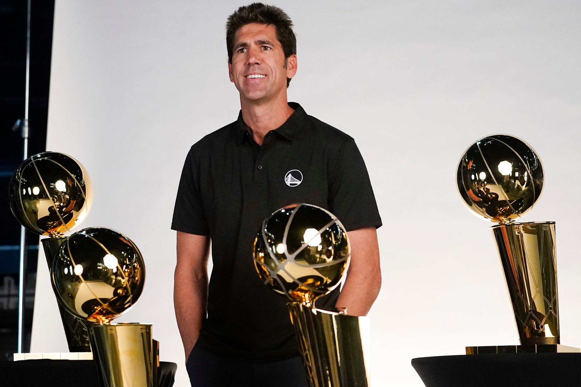 Myers poses with the four Larry OBrien trophies that the Warriors won under his watch.
