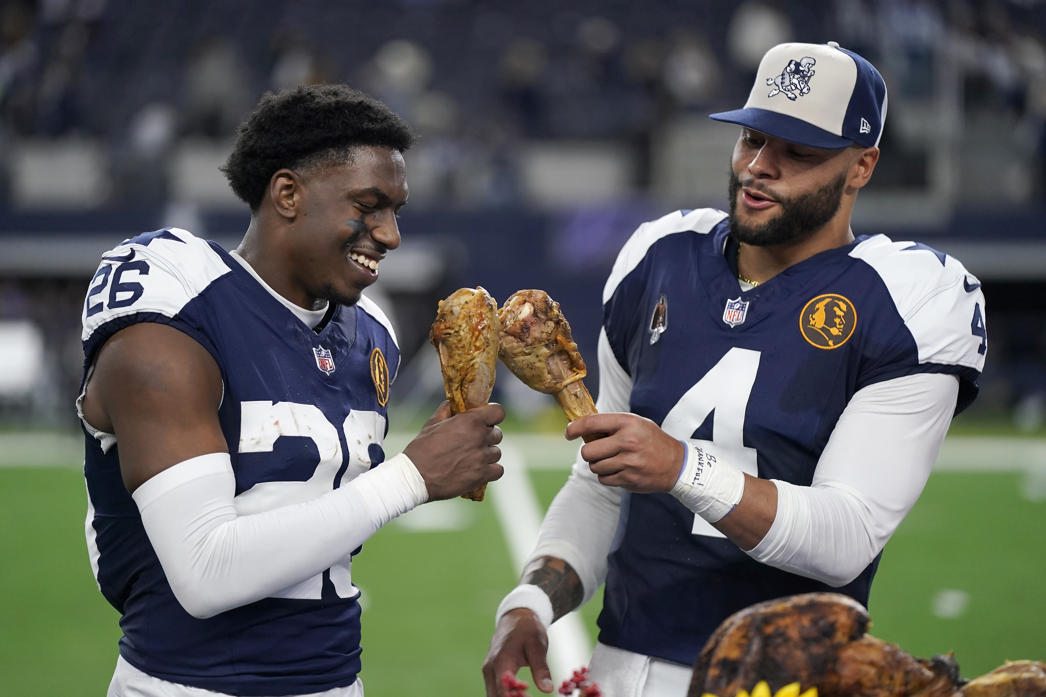 Dallas Cowboys cornerback DaRon Bland, left, and quarterback Dak Prescott celebrate by eating Thanksgiving turkey legs