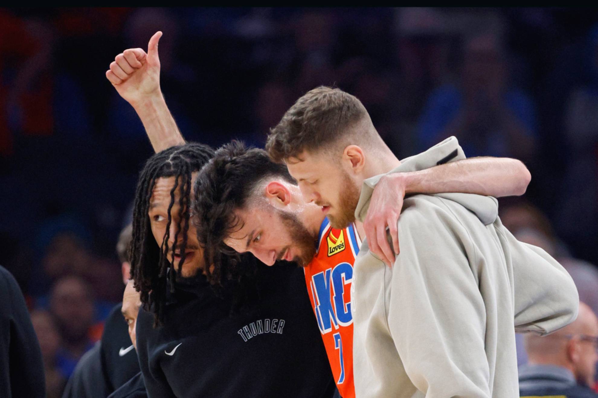 Chet Holmgren, center, gives a thumbs-up as he is helped off the court by Thunder forward Jaylin Williams /