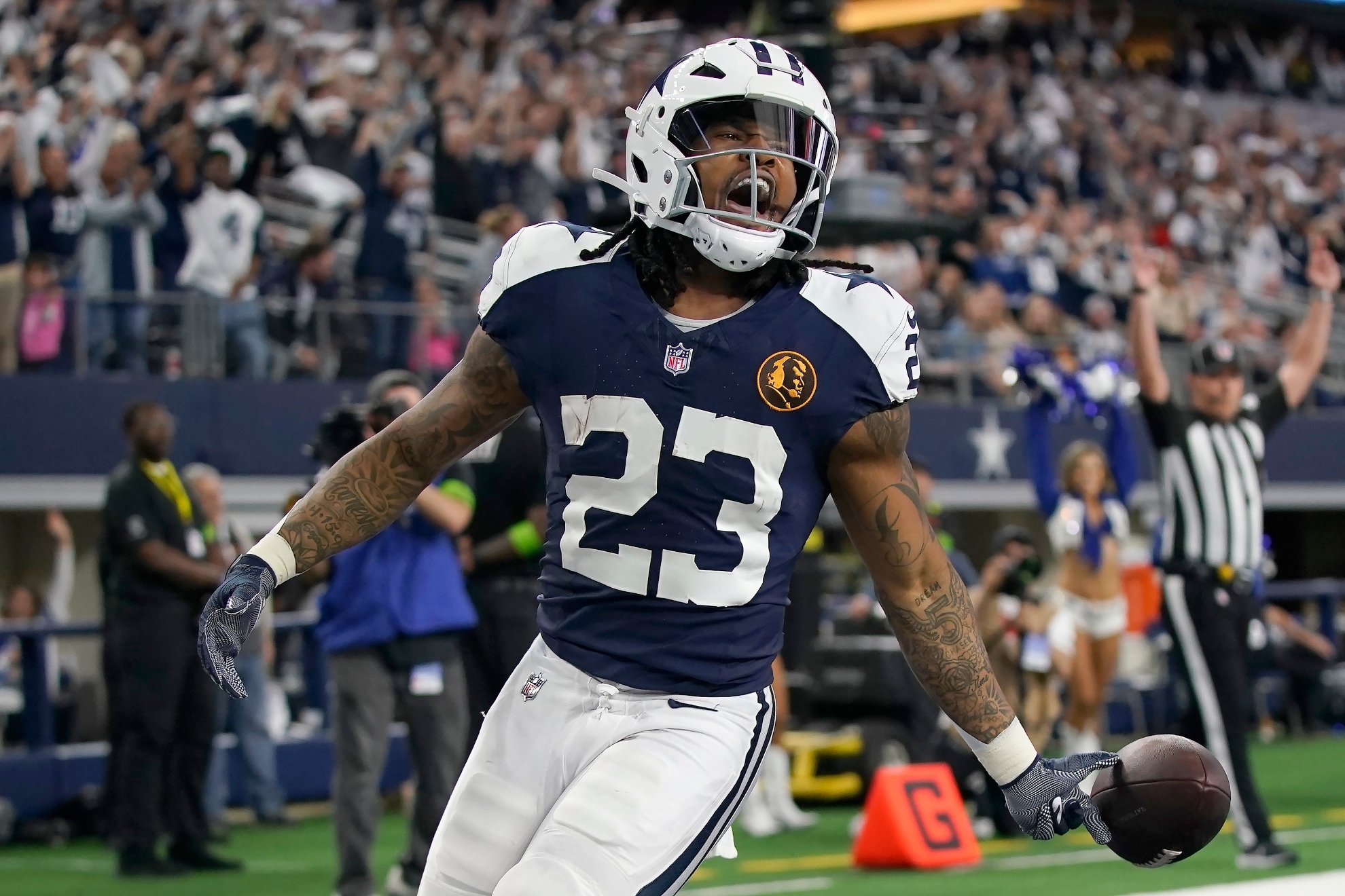 Dallas Cowboys running back Rico Dowdle (23) celebrates after scoring against the Washington Commanders during the first half of an NFL football game Thursday, Nov. 23, 2023, in Arlington, Texas. A John Madden Thanksgiving logo is shown on the jersey.