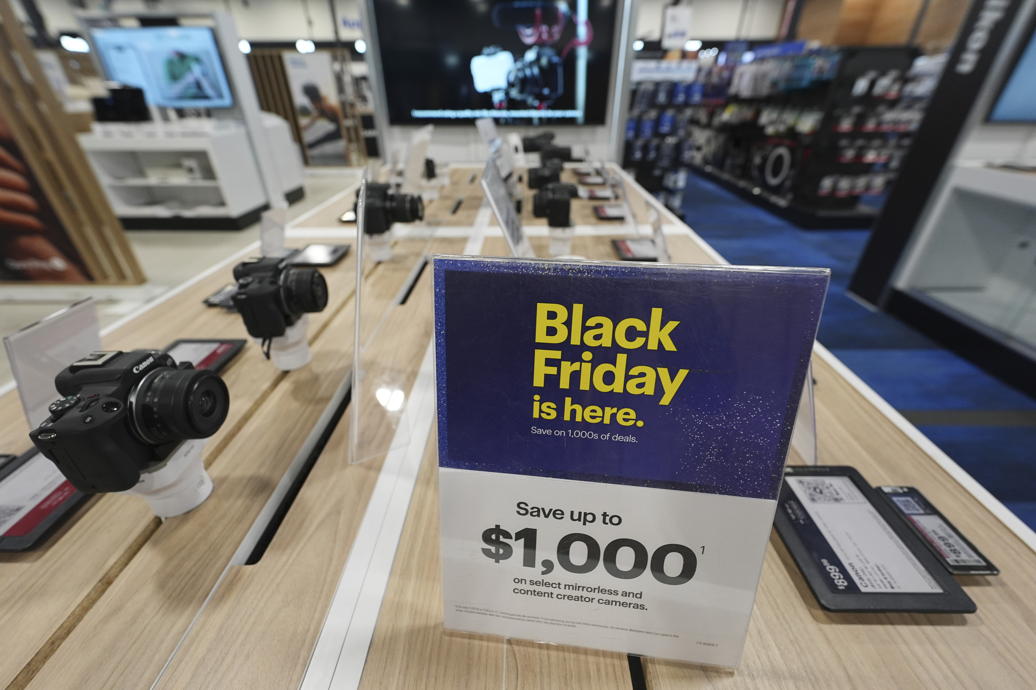 A sign promoting lt;HIT gt;Black lt;/HIT gt; lt;HIT gt;Friday lt;/HIT gt; deals sits on table with a display of mirrorless cameras in a Best Buy store Thursday, Nov. 21, 2024, in south Denver. (AP Photo/David Zalubowski)