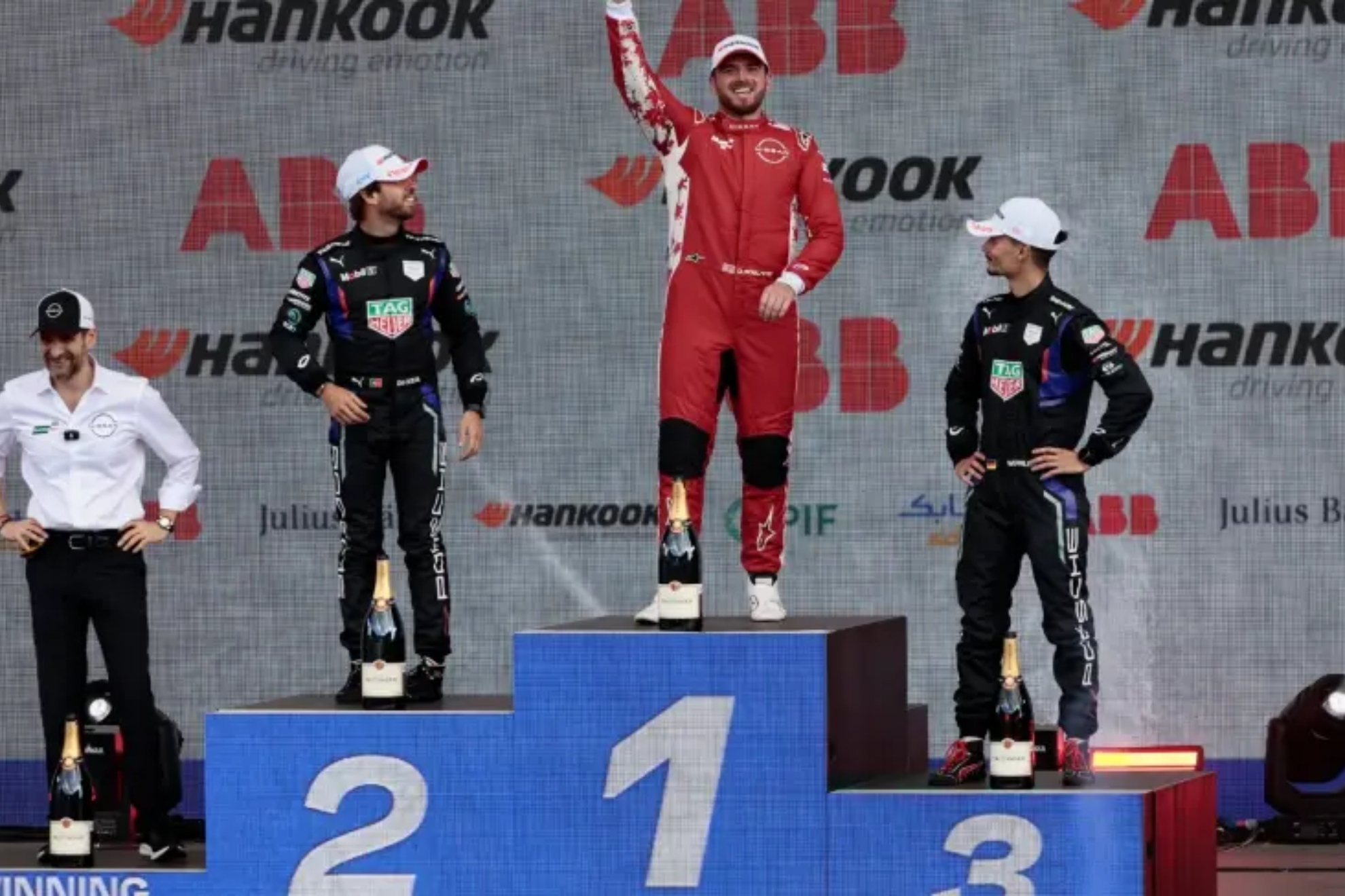 Rowland celebrates his victory on the podium, accompanied by Da Costa and Wehrlein