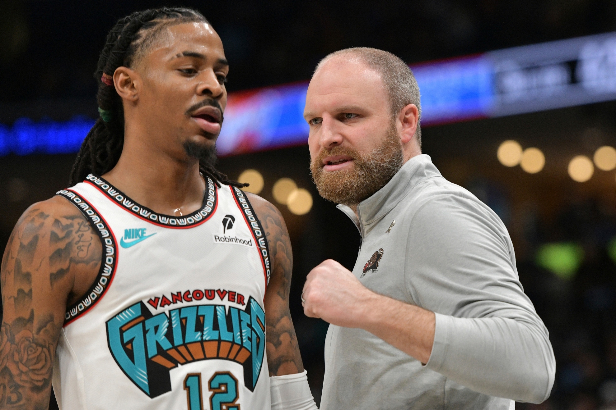 Memphis Grizzlies head coach Taylor Jenkins talks with guard Ja Morant who walks back to the bench during an NBA game.