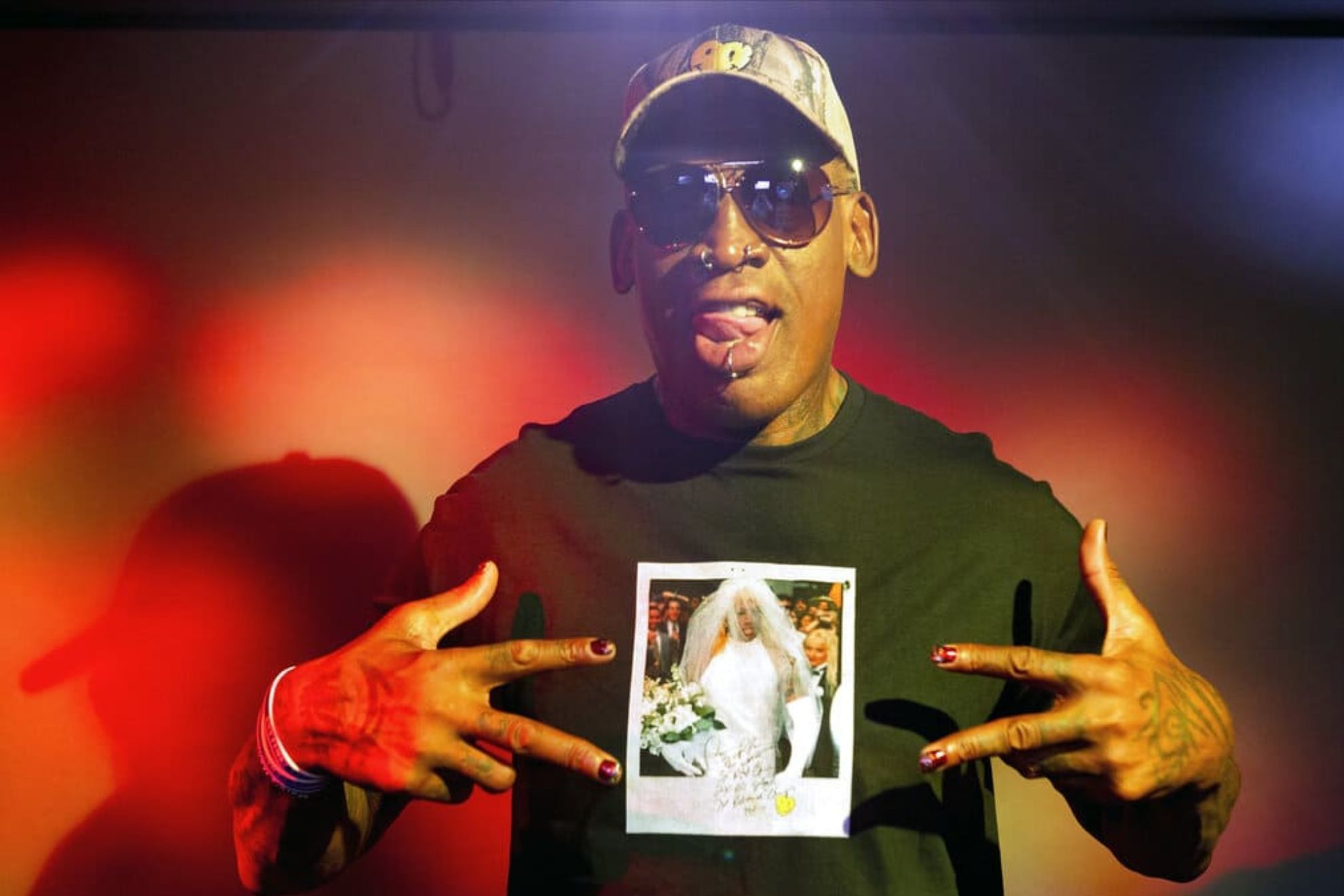 In this Monday, Sept. 9, 2019, photo, former NBA star Dennis Rodman poses wearing a T-shirt depicting himself in a wedding dress at a 1996 book promo event, in Los Angeles. After a career of spectacular highs and very public lows, Dennis Rodman keeps finding new ways to surprise. The former NBA star, featured in a new ESPN documentary, weighs in on his personal brand, bisexual athletes, North Korea and Trump. Rodmans spectacular personal highs and very public lows are the subject of the new ESPN 30 For 30 documentary Dennis Rodman: For Better or Worse. (AP Photo/Damian Dovarganes)