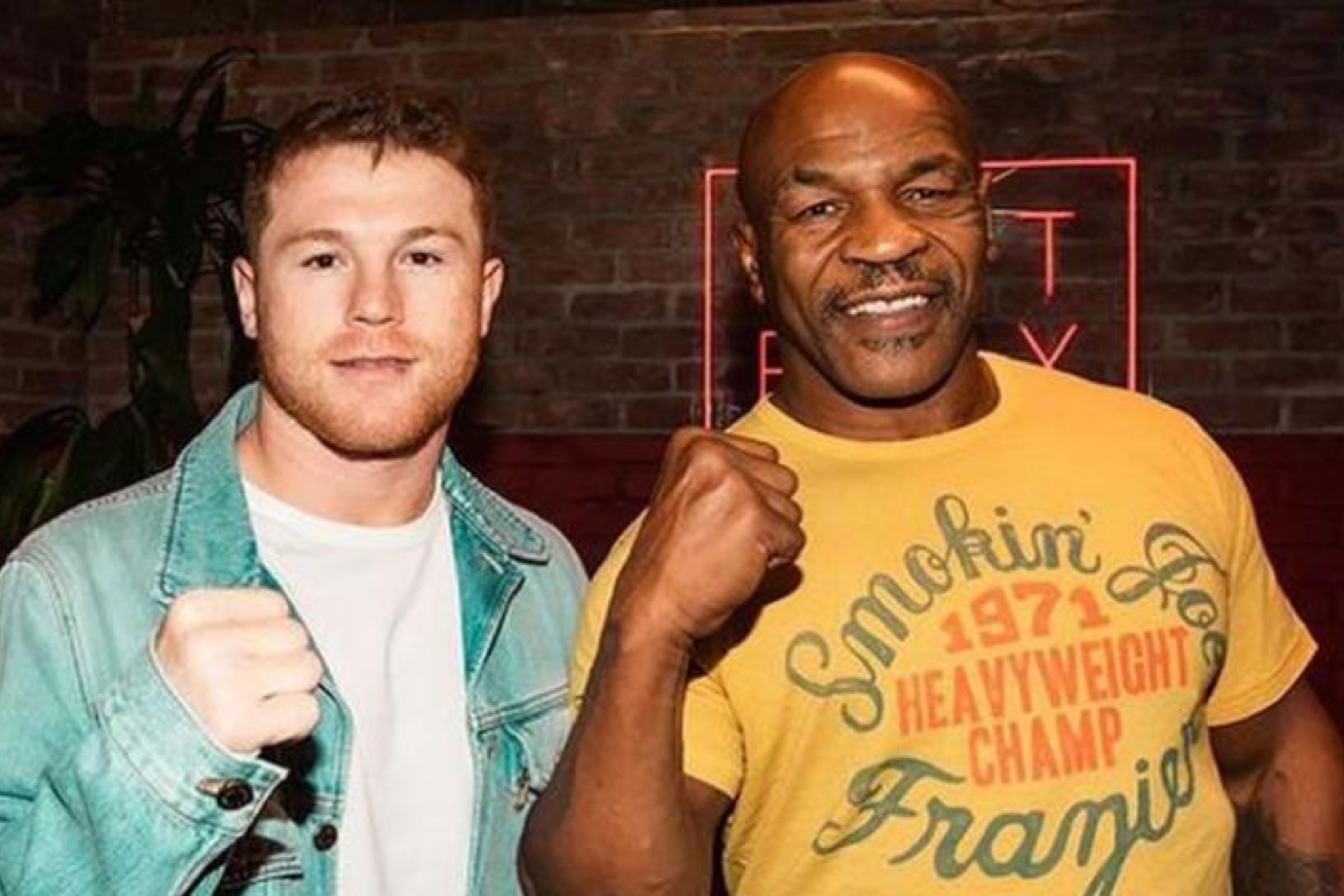 A young Canelo Alvarez poses with Mike Tyson during a bout at an event.