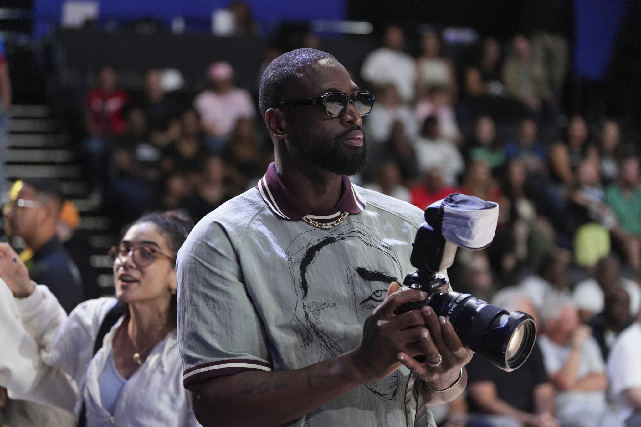 Dwayne Wade borrows a photographers camera to take pictures, during the Unrivaled 3-on-3 basketball semifinal