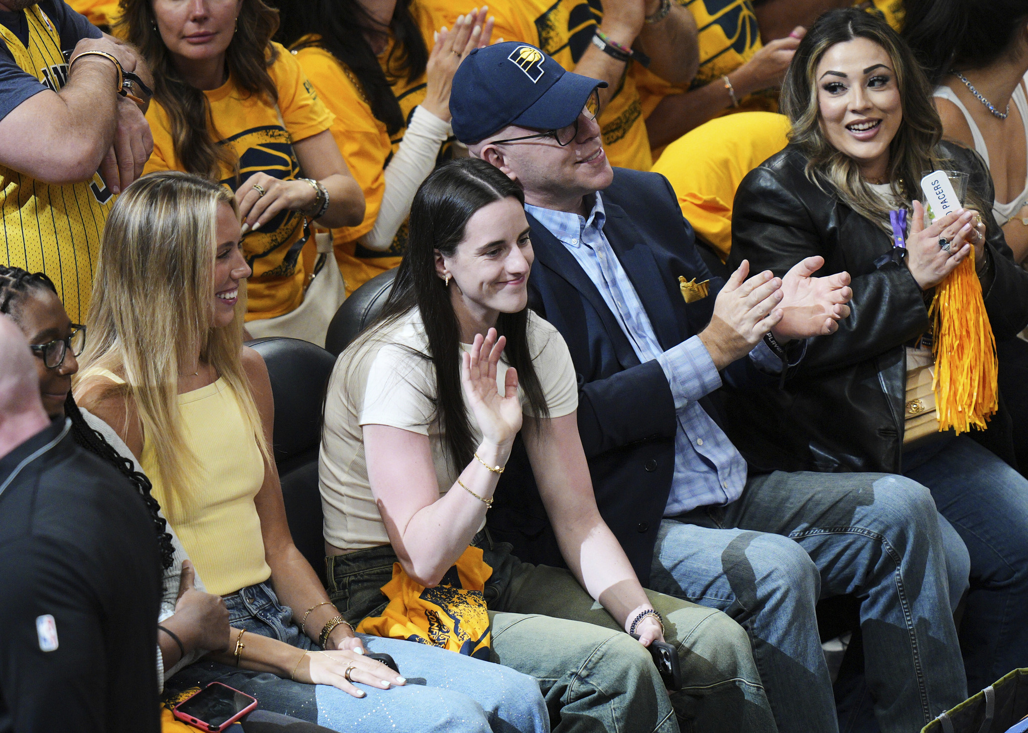 Caitlin Clark, center, waves from her seat during the first half of Game 6