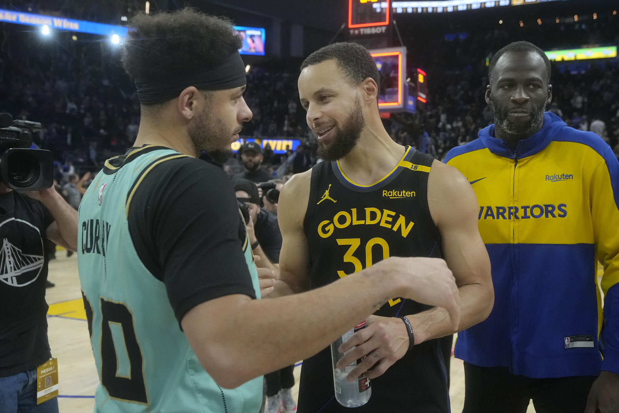 Charlotte Hornets guard Seth Curry, left, greets Golden State Warriors guard Stephen Curry