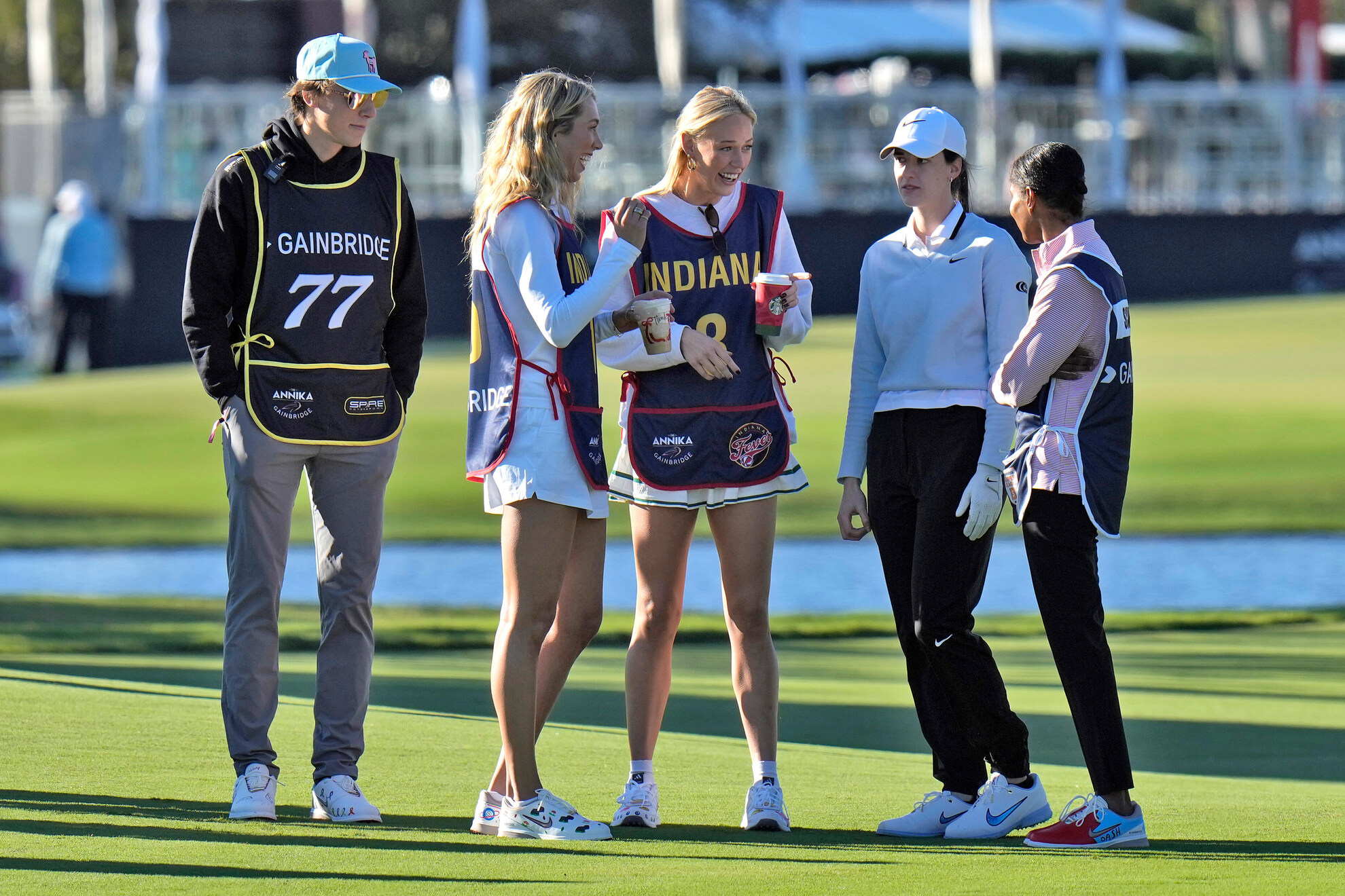 WNBA player Caitlin Clark talks to celebrity caddies, NASCAR driver Carson Hocevar, WNBA players Lexie Hull, Sophie Cunningham, and soccer star Briana Scurry