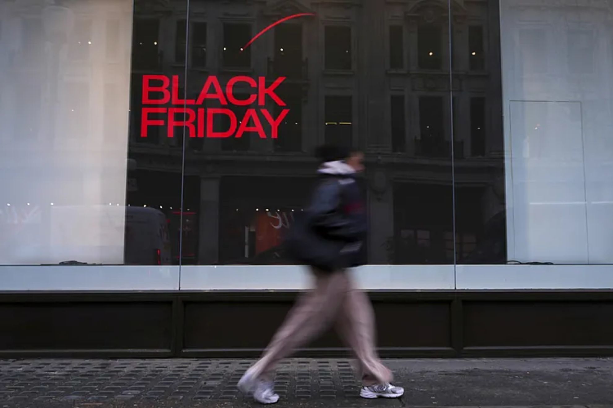 People pass a shop advertising a Black Friday. Sale on Oxford Street in London.