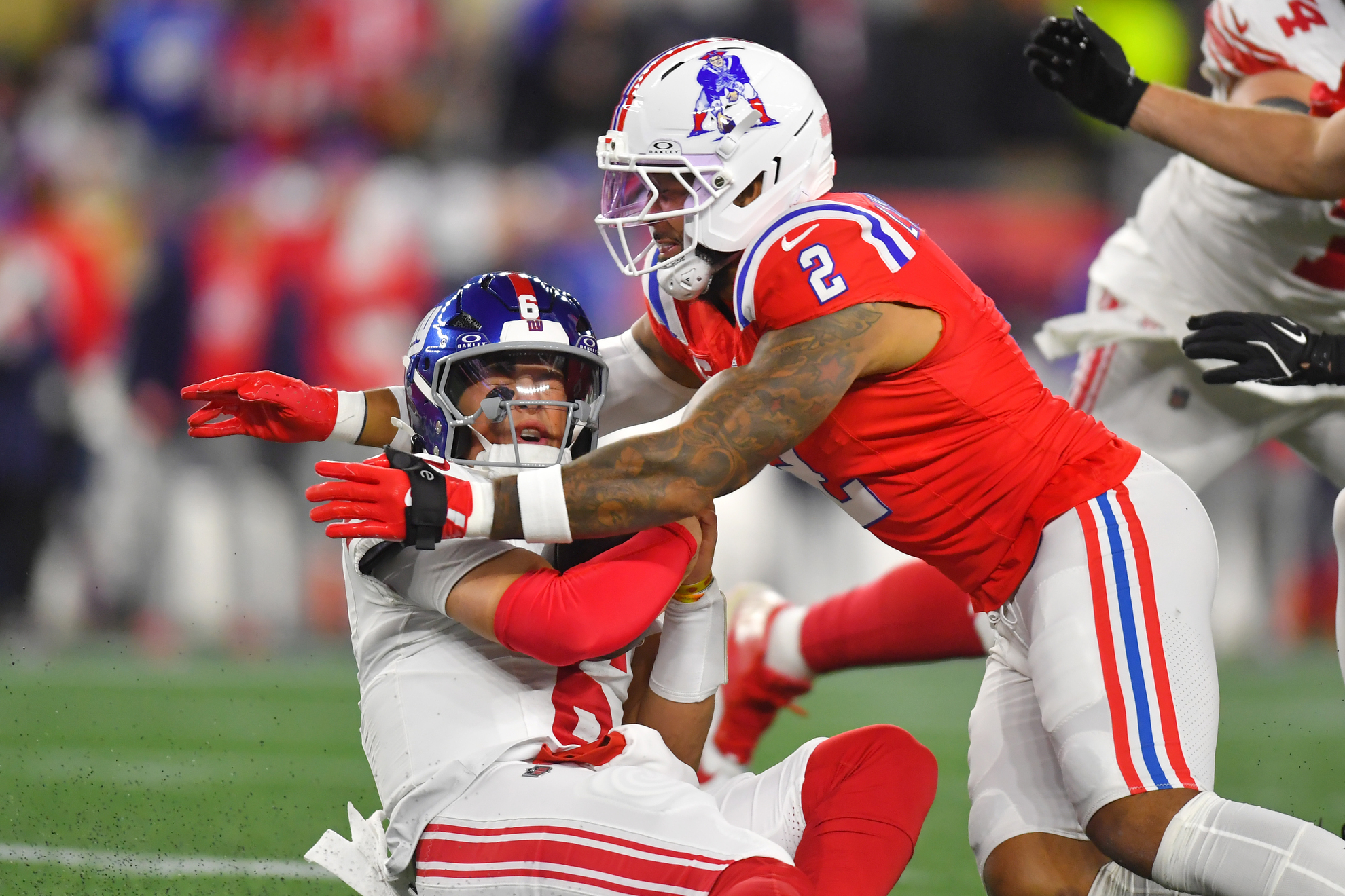 New York Giants quarterback Jaxson Dart, left, is sacked by New England Patriots linebacker Harold Landry III