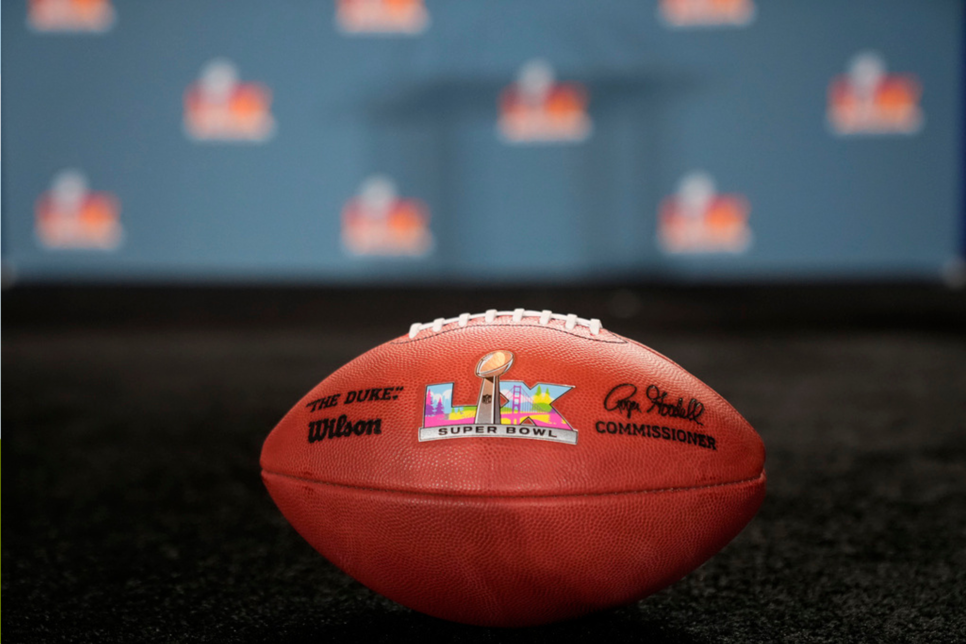A ceremonial football with the Super Bowl 60 logo sits on the stage