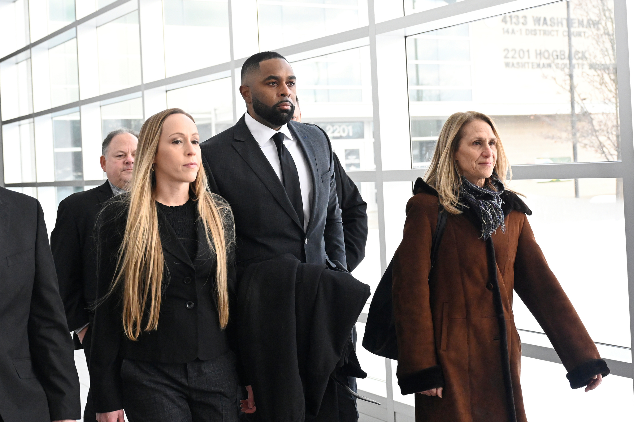 Former Michigan football coach Sherrone Moore walks with his wife, Kelli Moore, left, as he arrives at court