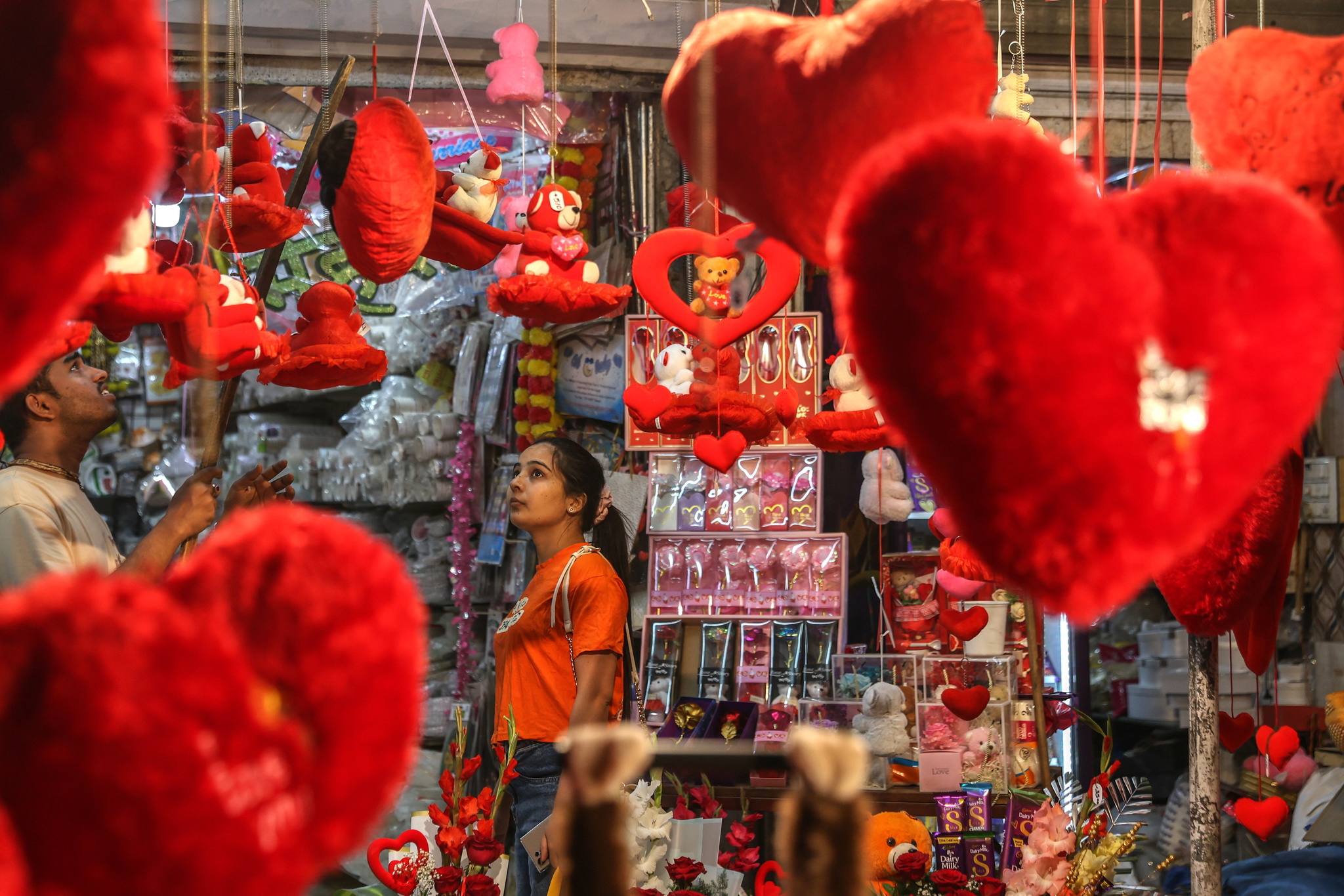 A woman checks heart-shaped gifts and plushies on display at a roadside shop on the eve of Valentines Day