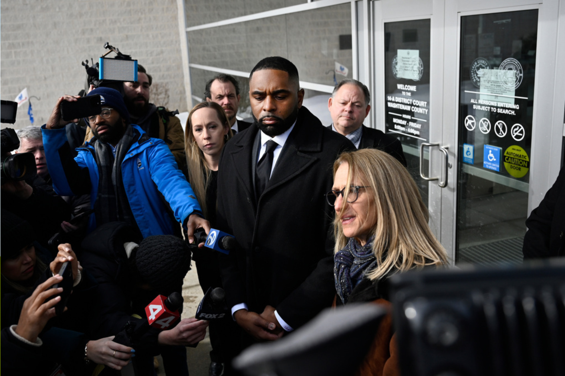 Former Michigan football coach Sherrone Moore, left center, stands with his attorney, Ellen K. Michaels