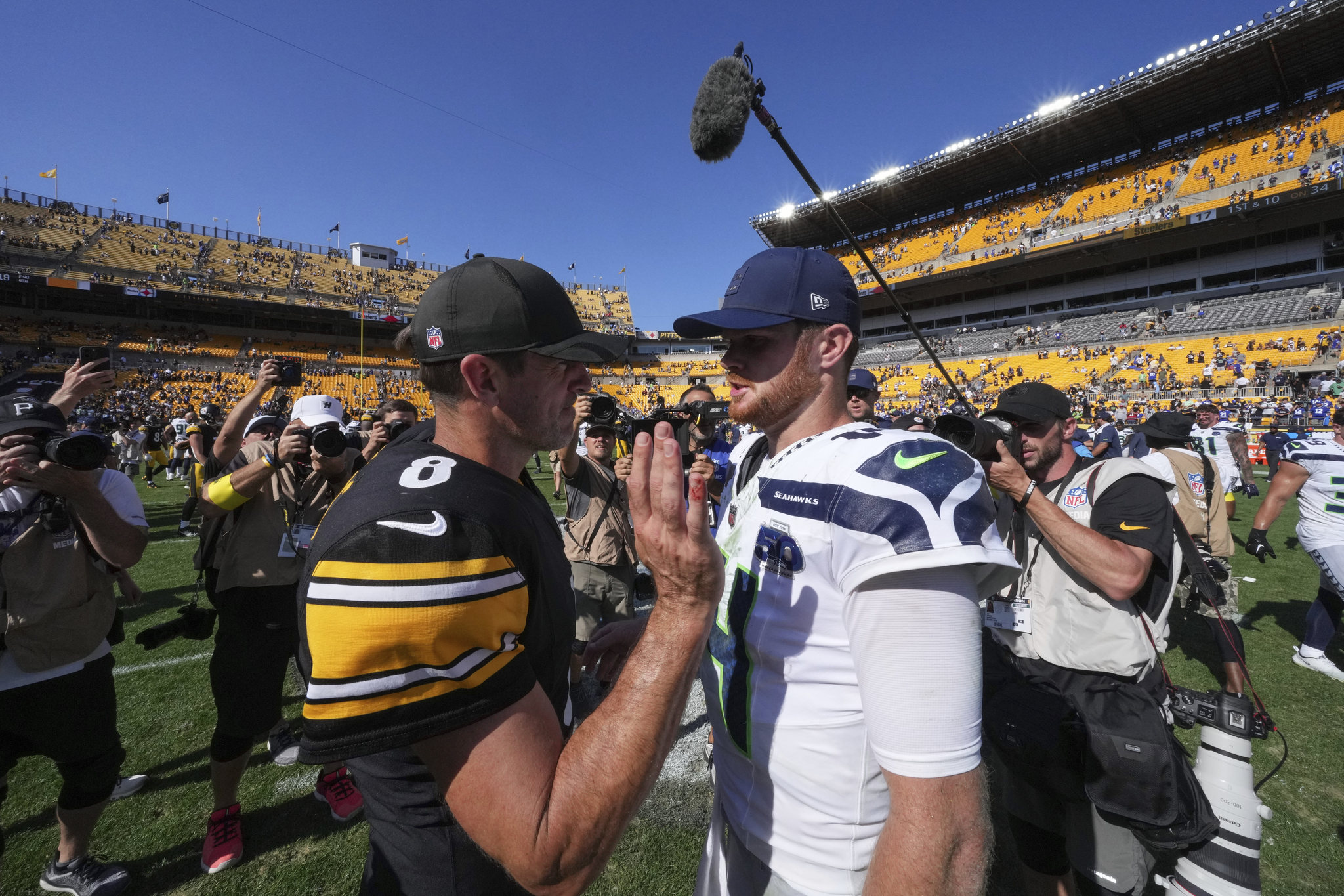 With a bloodied pinky finger, Pittsburgh Steelers quarterback Aaron Rodgers, left, talks with Seattle Seahawks quarterback Sam Darnold (14) after an NFL game